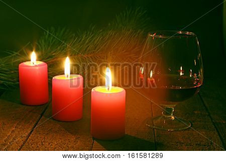 Brandy glass and candles on black background.