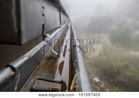 Gutter drainage system on the roof with dripping fog. Closeup