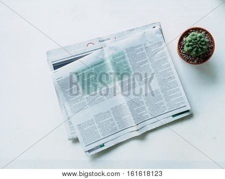 Top view stack newspaper and cactus pot on workplace white desk of ofiice