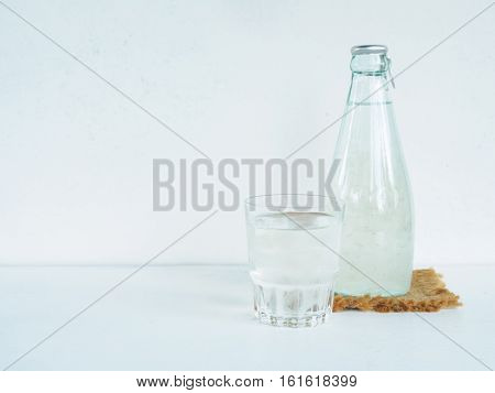 Bottle and glass health drink of grape juice or aloe vera on white desk with copy space