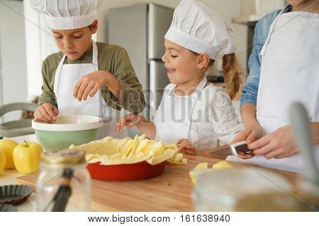 Kids in cooking class workshop preparing apple pie