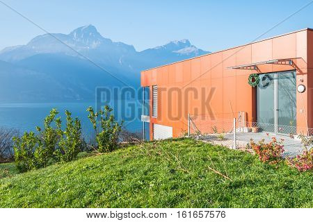 Fluelen Switzerland - 4. December 2016. Villa on the lake in the Swiss Alps. House a modern red. High windows with floor to ceiling and glass doors.