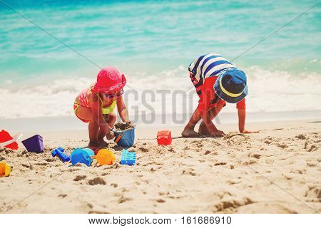 kids play with sand on summer beach, family at beach