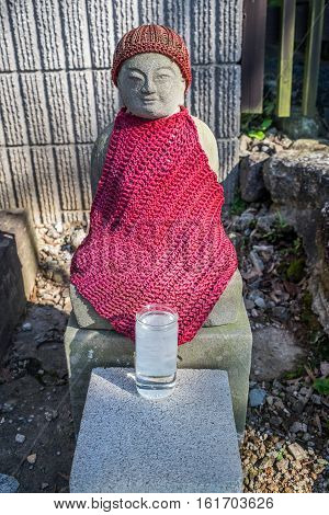 A buddahist statue with a red cloth  sake glass