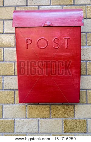 red mailbox with POST writing on a brown wall