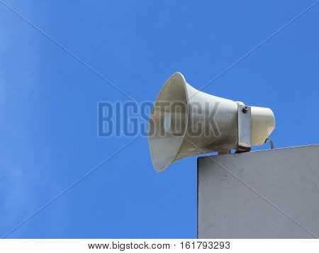 Speaker horn on building with blue sky background