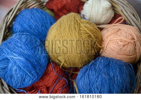 Multicilored wool clews in wood basket. Illustration about wool needlework and knitting