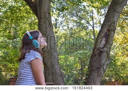 Girl listening to the music through headphones in the park