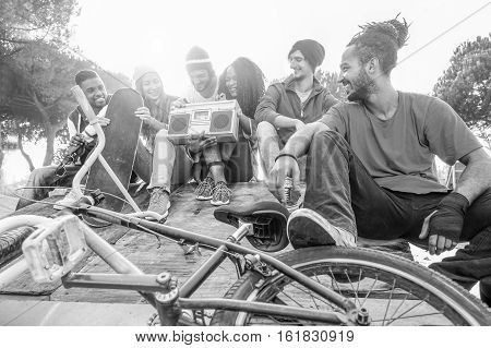 Happy friends listening music in new york skate city park - Breakerskaters and freestyle bikers having fun - Concept of sporty people socializing - Focus on rasta man - Black and white editing