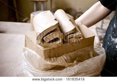 White clay preparation for work. Cutting layers of clay pieces for sculpting in the workshop of a potter Close-up. Twisted clay sheets on the old wooden table in pottery. Ukraine