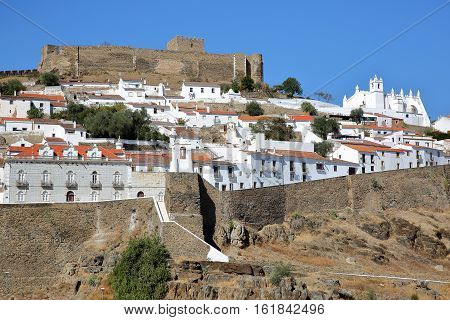 MERTOLA, PORTUGAL: View of the fortified village from the opposite bank of the river Guadiana with the castle and the Matriz Church in the background