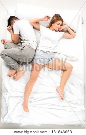 The young lovely couple lying in a white bed, love lconcept, top view
