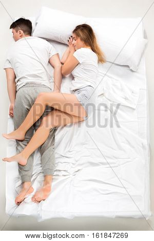The young lovely couple lying in a white bed, love lconcept, top view