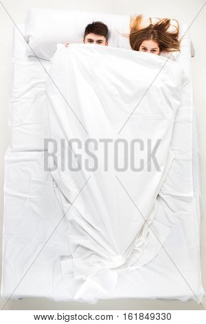 The young lovely couple lying in a white bed, love lconcept, top view