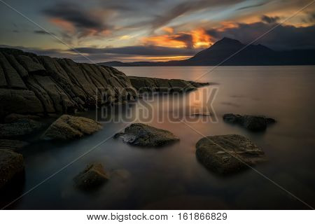 Rocky coastline of Loch Scavaig with Cuillin Mountains in background Isle of Skye Scotland
