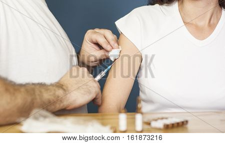 Doctor holding a syringe and preparing to vaccinate a women against flu