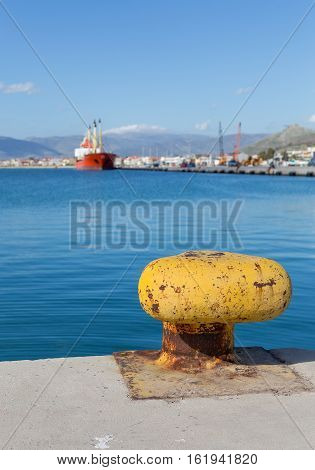 Yellow rusty bollard with sea and ship background