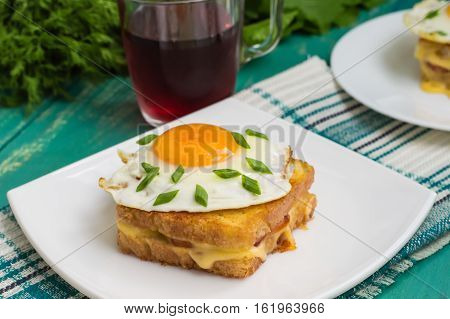 Croque-Madame, a French sandwich with greens and berry juice for breakfast. Wooden table. Top view