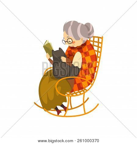 Cute Granny Sitting In A Cozy Rocking Chair And Reading A Book, Black Cat Lying On Her Knees, Lonely