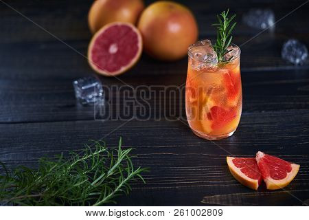 Refreshing Cold Cocktail With Grapefruit And Rosemary On A Black