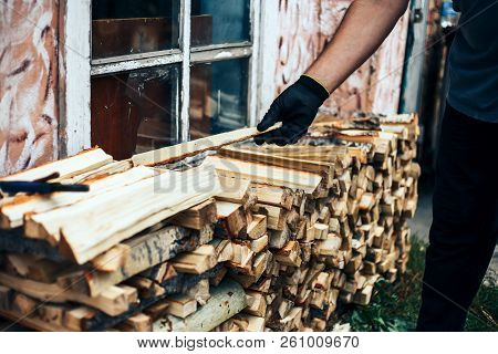 Man Hold Firewood, He Puts Cutting Wood Into Stack Of Wood Woodpile