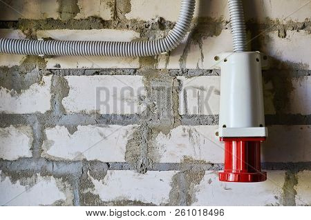 Red Industrial Appliance Connector Located On A Brick Wall.