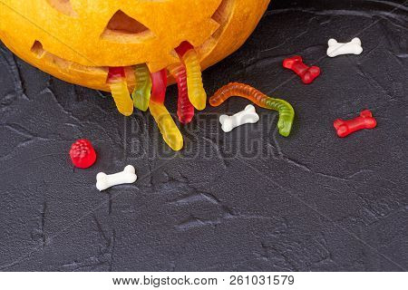 Pumpkin Puking With Jelly Worms. Halloween Pumpkin On Black Stone With Copy Space.