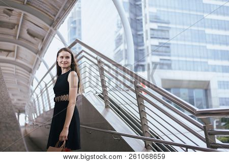 Confident Girl In Blackdress Smling And Holding Shopping Bags In City,lifestyle Concept