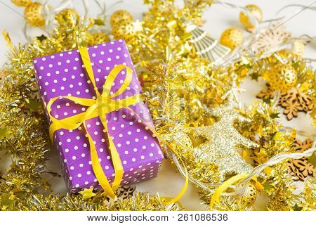 Violet Elegant Present With Yellow Ribbon On Golden Tinsesl And Garland