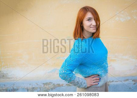 A Beautiful Young Woman With Red Hair In A Beige Blue Knitted Self-made Sweater From Natural Wool Po