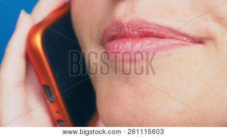 Close-up, Female Lips Without Makeup Talking On A Red Mobile Phone, Against A Blue Background.