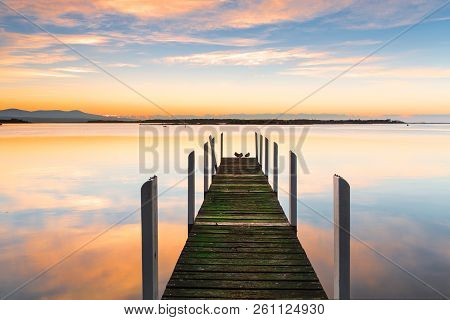 Perfect Serenity. Old Rustic Timber Jetty With Green Moss Growing On Its Weathered Timbers And Prett