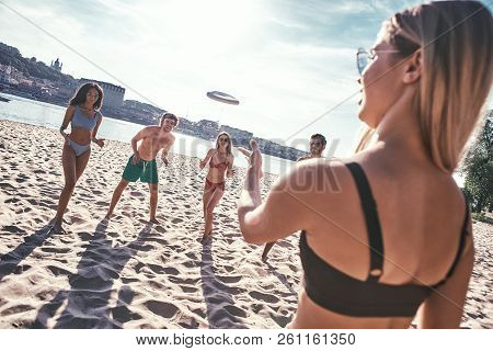 Time With Friends. Group Of Young People Playing Freesby On The Beach
