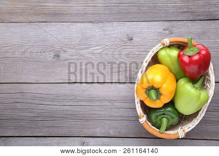 Fresh Pepper In A Basket On Grey Background. Red, Green, Yellow Paprika On Table.