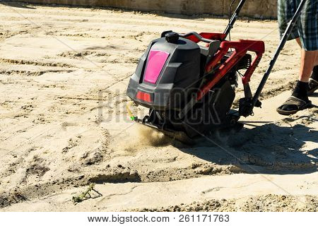 Builder With Vibratory Plates Seals The Base Sand For Pouring Concrete.