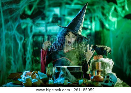 Young Witch With Awfully Face Reading Recipes Of Magic Drink In Creepy Surroundings And Smoky Backgr