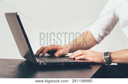 Man With Clock On His Hand Works On The Laptop At The Table In The Office. He Is Busy With The Task