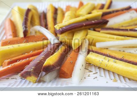 Colorful Yellow, Orange, Red And White Sliced Raw Carrots Plated And Sprinkled With Dry Rosemary Heb