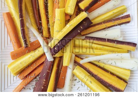 Colorful Yellow, Orange, Red And White Sliced Raw Carrots Plated And Sprinkled With Dry Rosemary Heb
