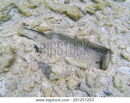 Glass Bottle On Tropical Seashore Sandy Bottom. Garbage In Sea. Clear Glass Bottle In Corals And San