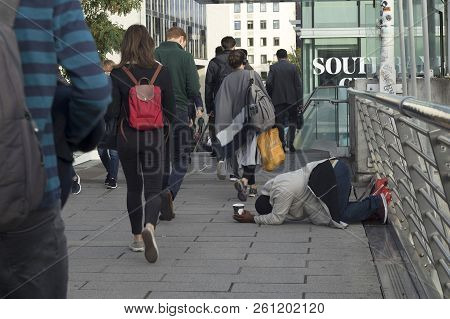 London, England - September 11 2018 A Beggar Man With A Glass In His Hand Asks For Alms. Crowd Pass 