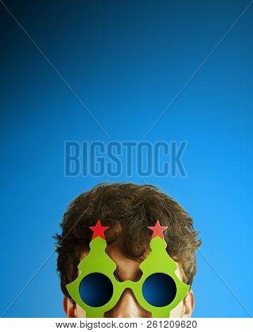 Portrait Of A Man In Christmas Tree Glasses. Portrait Of Cheerful, Attractive Man On Blue Background