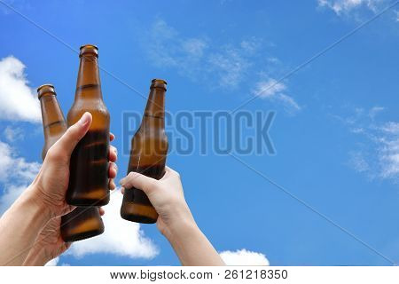 Hands Holding Three Beer Bottles And Happy Enjoying Harvest Time Together To Clinking Glasses At Out