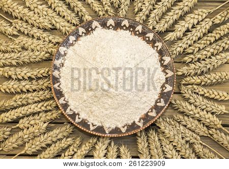 Harvest Of Wheat Spikelets And Flour On Wooden Background