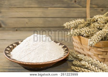 Harvest Of Wheat Spikelets And Flour On Wooden Background