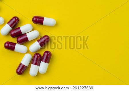 Medical, Pharmacy Or Health Care, Drug And Science Concept, Dark Red And White Capsules Pills On Yel