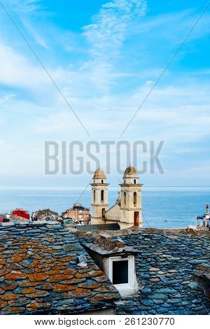 the characteristic twin bell towers of the Saint-Jean Baptiste Church in Bastia, Corsica, France, highlighting above the old slate rooftops of the old town, and the Mediterranean sea in the background