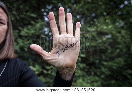 Womans hand raised with I believe written in marker supporting victims of abuse