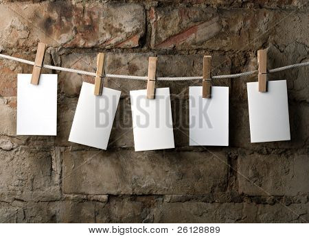 fünf Fotopapier beimessen Seil mit Kleidung Pins auf Backstein Hintergrund