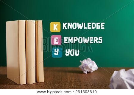 Three Books And Crumpled Papers On Wooden Table With E-learning - Learning Is Fun Lettering